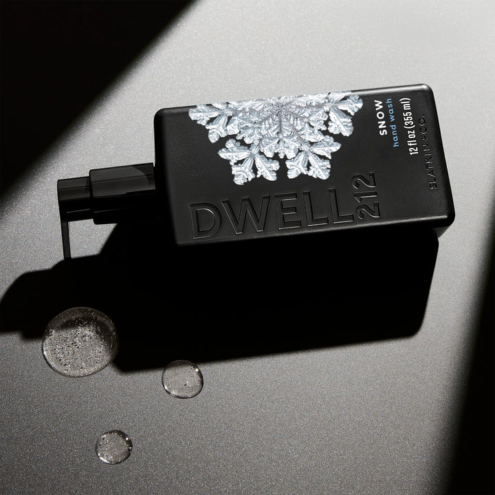 Black bottle of Dwell 212 SNOW fragrance hand wash with snowflake design on a gray background